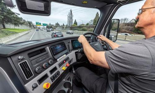 A driver in the cab of a Freightliner eCascadia electric truck